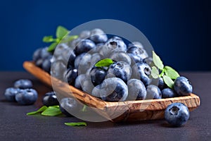 Blueberries with green leaves in wooden dish