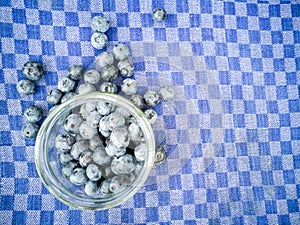 Blueberries in a jar on a checkered towel.