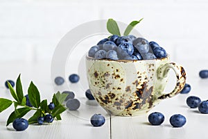 Blueberries with leaves in a ceramic cup