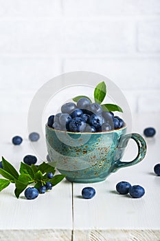 Blueberries with leaves in a ceramic cup