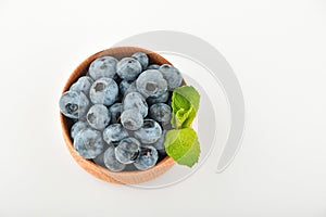 Blueberries and mint leaves in wooden bowl isolated on white