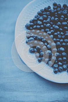 Blueberries in a plate on a table with a colored cloth.