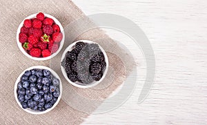 Blueberries, raspberries and blackberries on white background. Blueberry raspberry blackberry in white bowl.