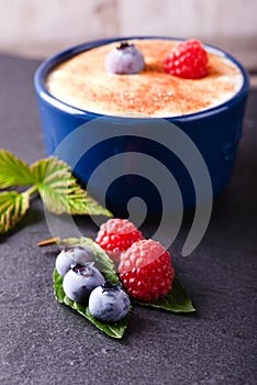 Blueberries and raspberries on slate stone with creamy dessert