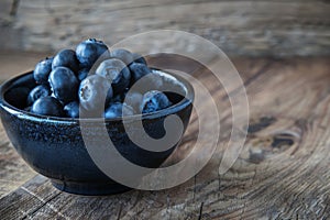 blueberries in rustic bowl on wooden table, low key style, generative AI