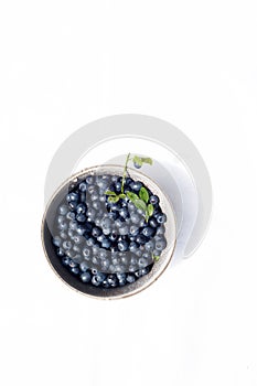 Blueberries in a small clay cup on a white background. Freshly picked berry in the forest.