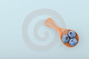 Blueberries on spoon isolated blue background with copy space