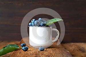 Blueberries in vintage white mug on old wooden boards. Organic food concept