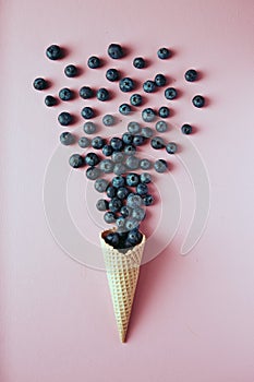 Blueberries in waffle cone on pink background, healthy snack, concept flat lay photography and content for food blog