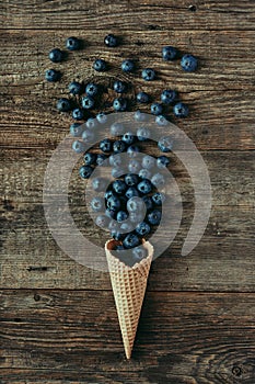 Blueberries in waffle cone on wooden table, healthy snack, concept flat lay photography and content for food blog