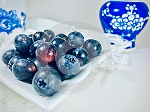 Blueberries on white square saucer.