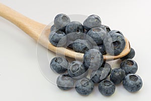 Blueberries in wooden spoon on white background