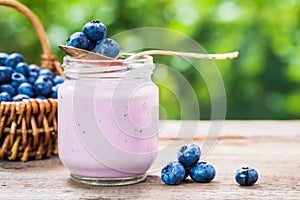 Blueberries yogurt in jar, basket of berries and saucer
