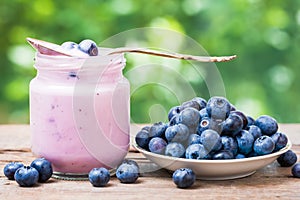 Blueberries yogurt in jar and saucer with bilberries