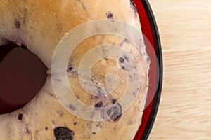 Blueberry bagel on red dish top close view