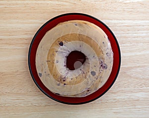 Blueberry bagel on red dish top view