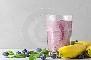 Blueberry, banana and spinach smoothie or milkshake in a glass with fresh fruits and berries. Healthy drink