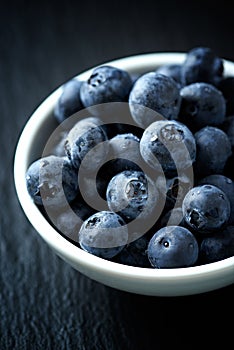 Blueberry, blueberries, fresh berry, berries, bilberry, bilberries served in a small ceramic bowl on black background.