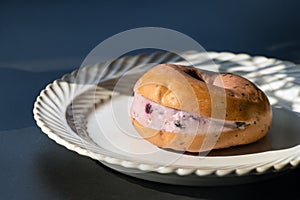 Blueberry cheese bagel on white plate