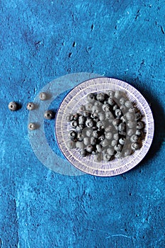 Blueberry on a decorative ceramic plate. Simple still life with summer berries. Textured blue background with copy space.