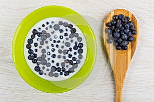 Blueberry with milk in bowl, blueberries on bamboo spoon