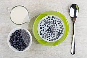 Blueberry with milk in bowl, bowl with berries, milk, spoon