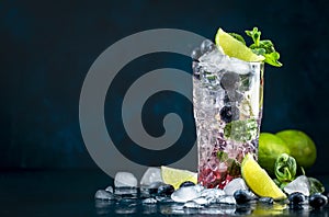 Blueberry Mojito cocktail drink with lime, white rum, soda, cane sugar, mint, and ice in glass on deep blue background. Summer