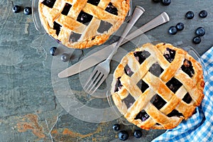 Blueberry pies, top view corner border over a dark background