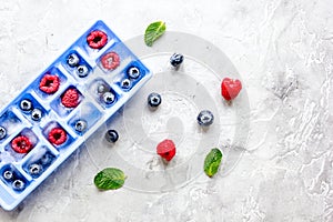 Blueberry and raspberry in ice tray on stone background top view mock-up