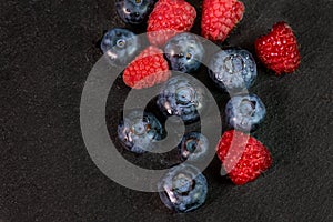 Blueberry and raspberry isolated on black background. Raw berries mix isolated