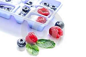 Blueberry and raspberry in ice tray on stone background