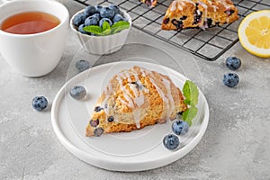 Blueberry scones with lemon glaze on top on a gray concrete background. Delicious breakfast
