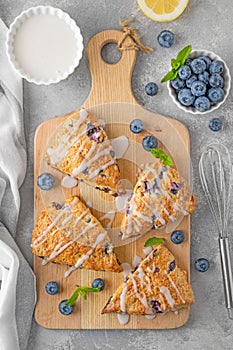 Blueberry scones with lemon glaze on top on a gray concrete background. Delicious breakfast