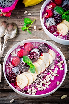 Blueberry smoothie bowl with banana, raspberry, pitaya, blackberry, almonds, sunflower and chia seeds