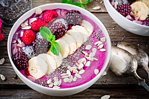 Blueberry smoothie bowl with banana, raspberry, pitaya, blackberry, almonds, sunflower and chia seeds