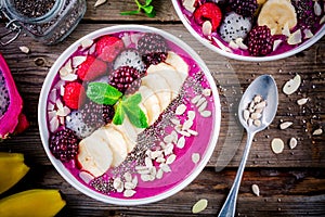 Blueberry smoothie bowl with banana, raspberry, pitaya, blackberry, almonds, sunflower and chia seeds
