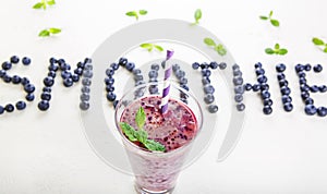 Blueberry smoothie in a glass jar with a straw and sprig of mint