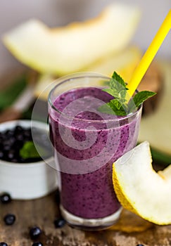 Blueberry smoothie in a glass jar with a straw and sprig of mint