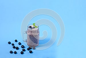 Blueberry smoothie with mint in mason jar glass with berries and mint. Above view on blue table.