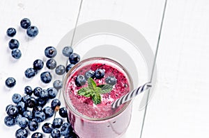 Blueberry smoothie on a wooden white background. Glass of smoothie with berry and mint. Fruit Healthy food. Breakfast.