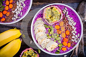 Blueberry smoothies bowl with sea-buckthorn, banana, passion fruit, chia seeds, pumpkin seeds, sunflower and flax seeds