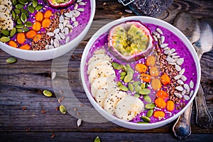 Blueberry smoothies bowl with sea-buckthorn, banana, passion fruit, chia seeds, pumpkin seeds, sunflower and flax seeds