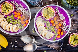 Blueberry smoothies bowl with sea-buckthorn, banana, passion fruit, chia seeds, pumpkin seeds, sunflower and flax seeds