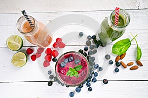Blueberry, spinachy and orange smoothie on a wooden white background. Glasses of smoothie with berry and mint. Berry, leaf and lim