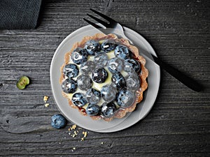 Blueberry tart on dark wooden table