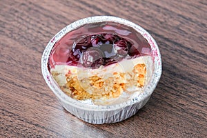 Blueburry cheese cake in foil cup homemade with wooden table for dessert background or texture - food concept