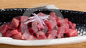 Bluefin tuna tartare with chopped red onion, served on a fish-shaped plate photo