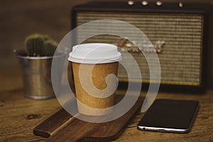 Bluetooth speaker acton, brown coffee cup, phone, smartphone, wooden board and a cactus