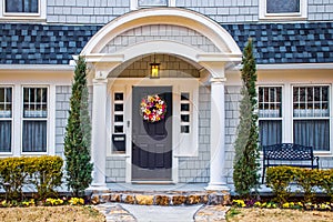 Bluish Grey cedar shake shingled home with drama added by gently curved gable porch roof in early spring with pansies in flower