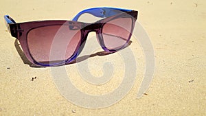 Bluish violet shade with shiny plastic frame on sand in desert in sunlight